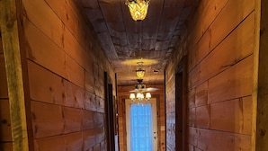 Un pasillo de madera con una alfombra que conduce a una puerta con cortinas.