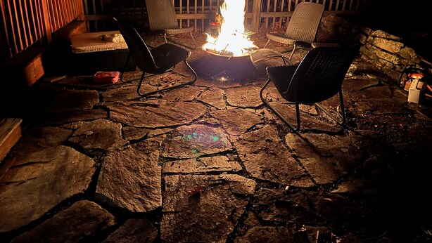 Un patio de piedra con un pozo de fuego y dos sillas.
