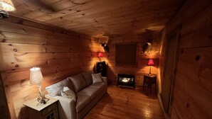 Una habitación acogedora de estilo cabaña, con suelo de madera, un sofá, una pequeña mesa y dos lámparas.