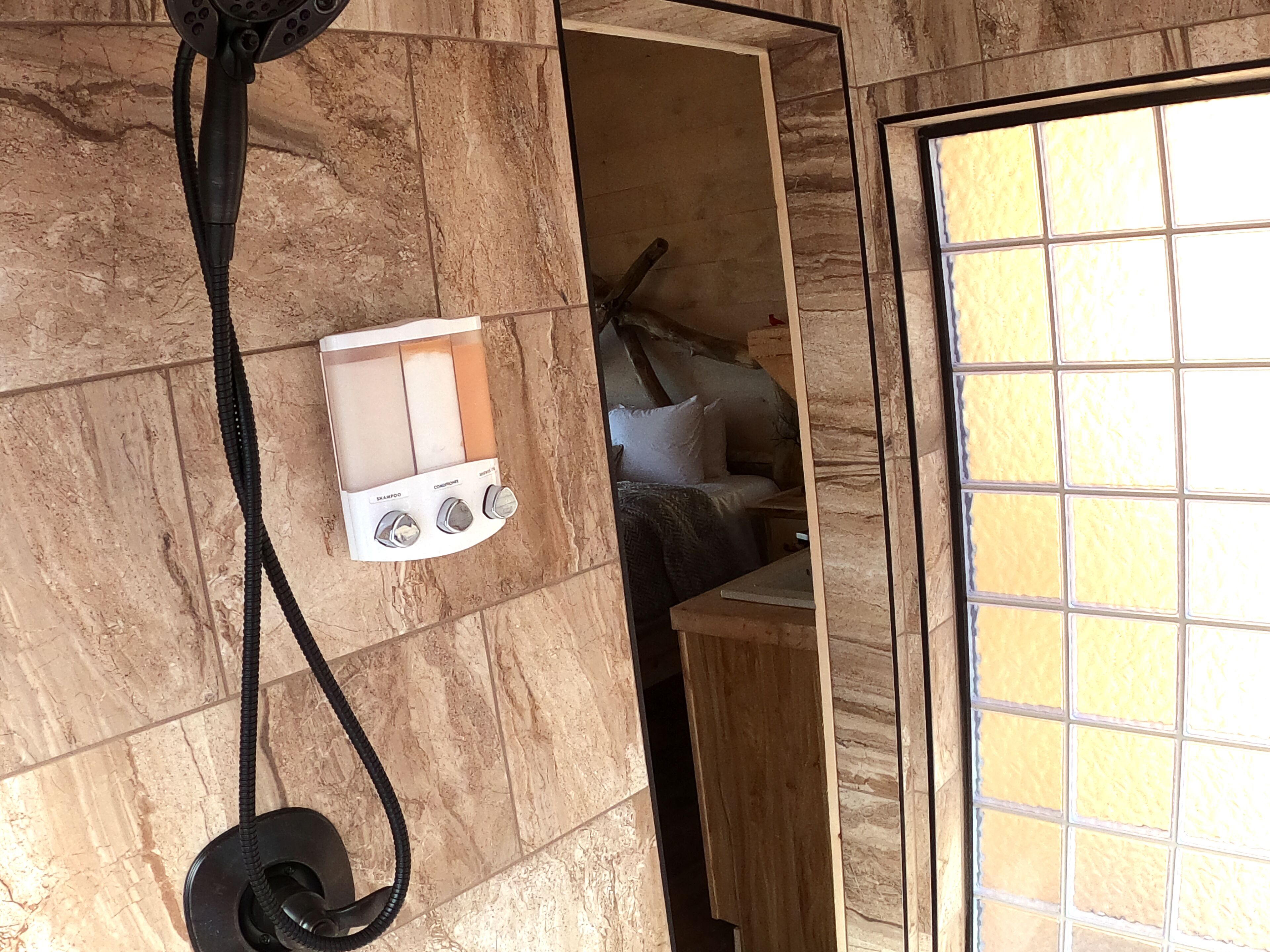 A bathroom with a shower, a towel rack, and a window.
