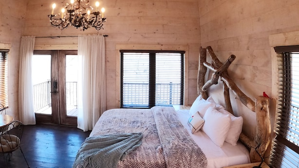 A wooden room with a bed, a chandelier, and a wooden headboard. - The Riverbirch Treehouse-close to town yet steps away from total wilderness (Nixa)