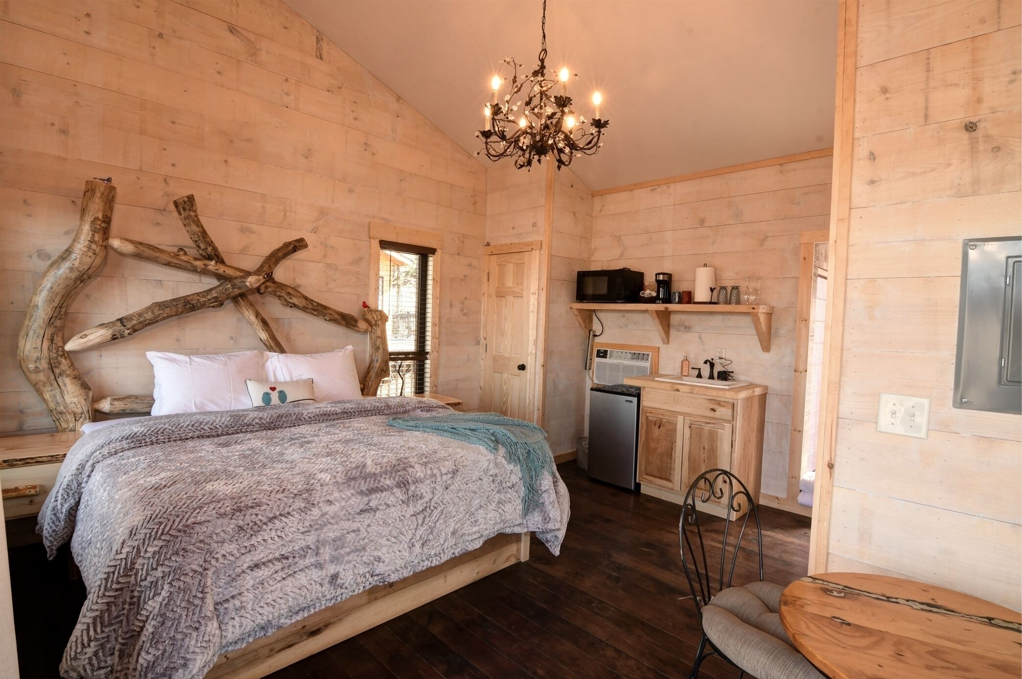 A cozy wooden room with a bed, a desk, and a dining table.