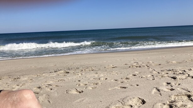 Ein Sandstrand mit Fußspuren, die zum Wasser führen.