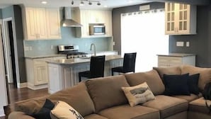 Ein modernes Wohnzimmer mit Ecksofa, einer Küche im Hintergrund und einem Essbereich.