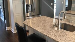 Eine moderne Küche mit Granit Arbeitsplatten, Edelstahlgeräten und einer Bar.