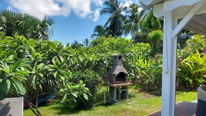 A garden with a barbecue area, a wooden deck, and lush greenery.