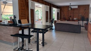 A modern kitchen with a dining area, wooden walls, and a view of the outdoors.