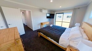 Una habitación de hotel con una cama, un aparador de madera, un televisor y una ventana con cortinas.