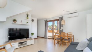 A modern living room with a flat-screen TV, wooden furniture, and a balcony with curtains. - Casa Kaliste (Puerto Calero)