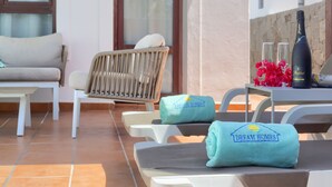 A sunlit outdoor seating area with lounge chairs, a table with a bottle of champagne, and towels branded 'Dream Homes'. - 7 PIEDRAS (Playa Blanca)