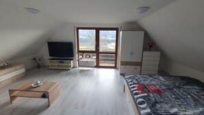 Ein Schlafzimmer mit Bett, Fernseher, Kleiderschrank und Fenster mit Aussicht ins Freie.