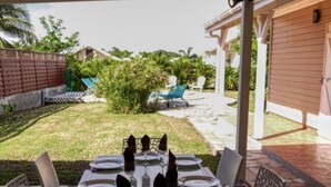 A covered outdoor dining area with a table set for six, surrounded by chairs. - Villa rose des sables with private pool (Saint-François)