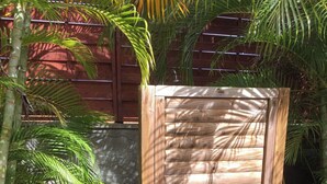 A wooden gate with a metal frame, set in a garden with stone stepping stones and tropical plants. - Villa rose des sables with private pool (Saint-François)