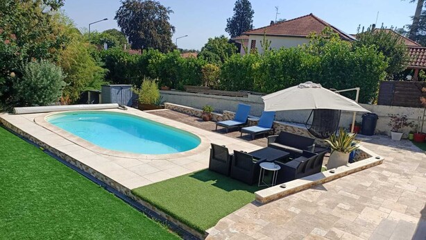 Ein Garten mit Schwimmbad, einer Terrasse mit Gartenmöbeln und einem gepflegten Rasen.