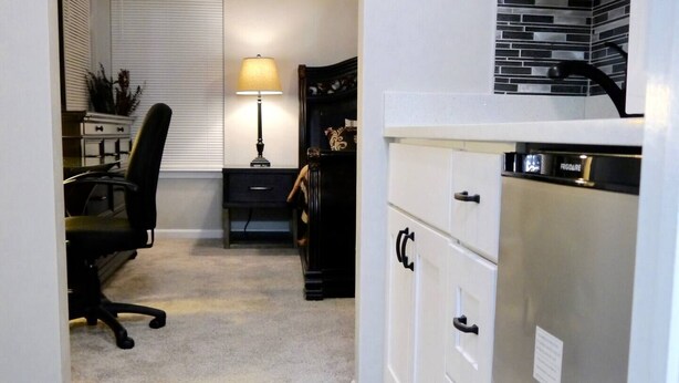 Cocina compacta con refrigerador, horno integrado y microondas. Cuenta con un pequeño comedor con una silla y una mesa.