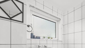 A modern bathroom with a white sink, a bathtub, and a toilet. There is a window above the sink and a mirror on the wall. - Three Bedroom Apartment by Klass Living Serviced Accommodation Coatbridge - Berwick Apartment With WiFi &Parking (Coatbridge)