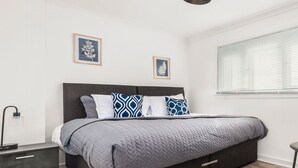 A modern bedroom with a large bed, a bedside table, a lamp, and two framed botanical prints on the wall. - Three Bedroom Apartment by Klass Living Serviced Accommodation Coatbridge - Berwick Apartment With WiFi &Parking (Coatbridge)