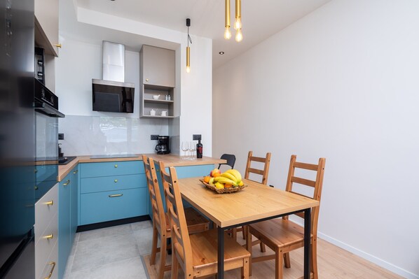 Una cocina moderna con armarios azules, una mesa de comedor de madera con sillas y una cesta de frutas sobre la mesa.