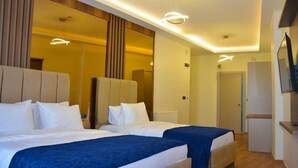 Habitación de hotel con dos camas, un espejo grande y un televisor en la pared.
