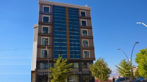 Un hotel de varios pisos con fachada moderna, que destaca una banda vertical central de ventanas y balcones en cada nivel.