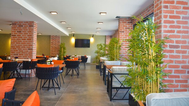 Un restaurante moderno con paredes de ladrillo, varias mesas y sillas.
