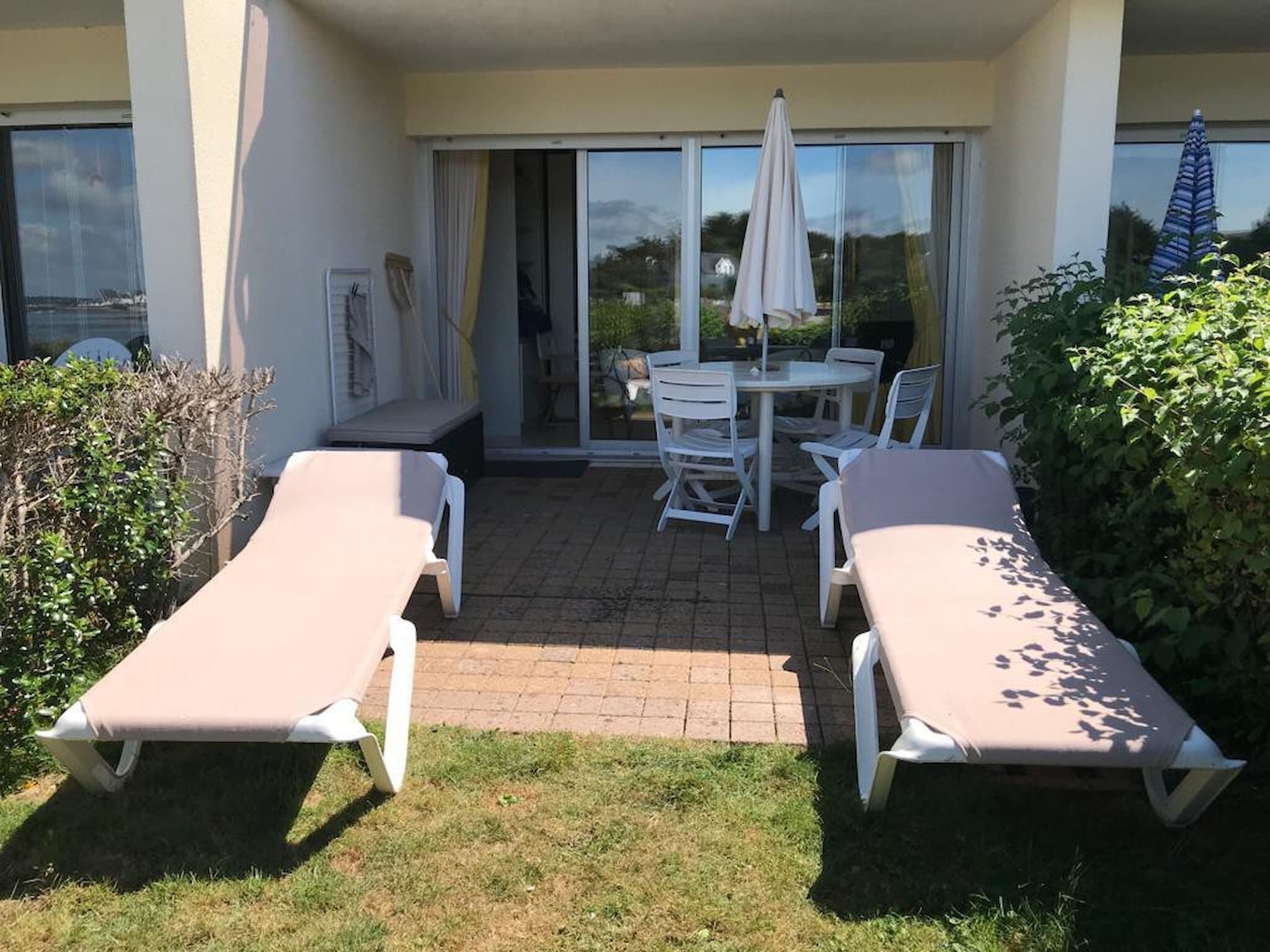 Un patio con dos tumbonas, una mesa y sillas.