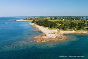 An aerial view of a coastal area with a lighthouse, sandy beach, and surrounding greenery. - Lovely sea view studio in Locmariaquer (Locmariaquer)