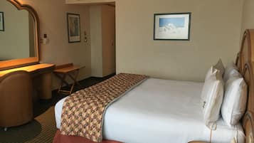Habitación de hotel con cama, escritorio, silla, espejo y un cuadro en la pared.