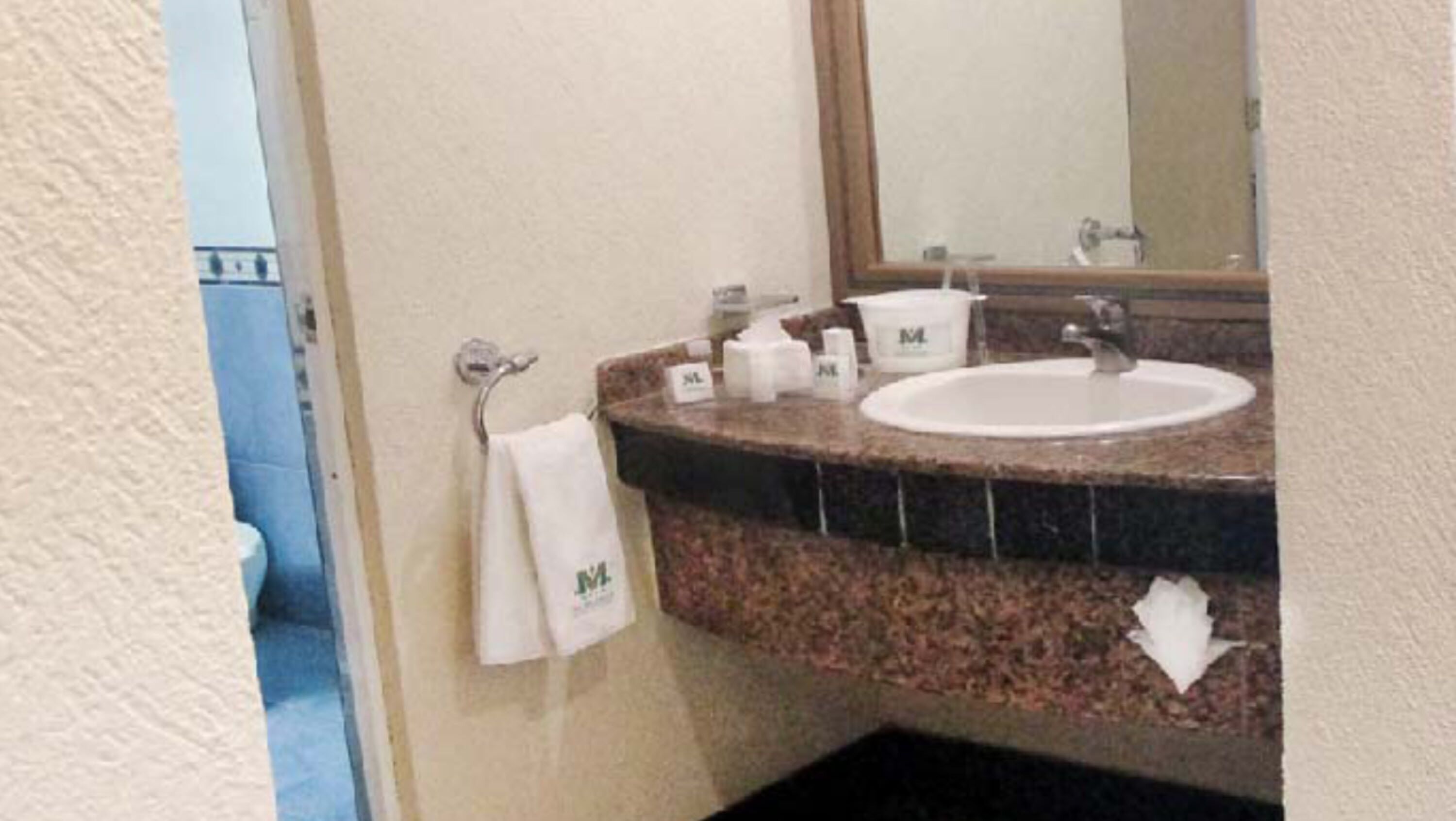 A bathroom with a sink, mirror, and towel rack.
