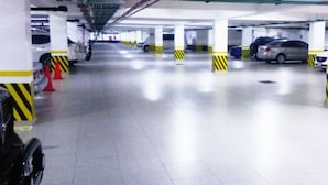 A multi-level parking garage with white pillars and yellow and black striped bollards. - Hotel La Muralla (Toluca)
