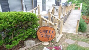 Una terraza de madera que lleva a una casa con un cartel que dice "CREEK SIDE".