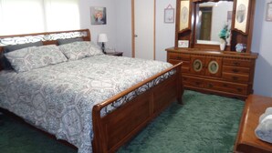 Un dormitorio con una cama de madera, un tocador y un espejo.