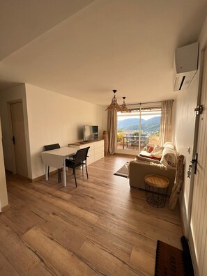 Relax in this inviting living area with a dining table, sofa, and TV, offering a view of the surrounding mountains and sky.