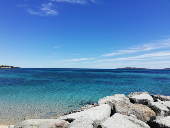 Une mer d’un bleu profond, bordée d’une côte rocheuse et s’étendant jusqu’à une terre lointaine.