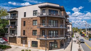 A multi-story building with balconies, a ground-level entrance, and a visible storefront. - Nest on West - Small town charm | Downtown Condo | Walk to shops (Blue Ridge)
