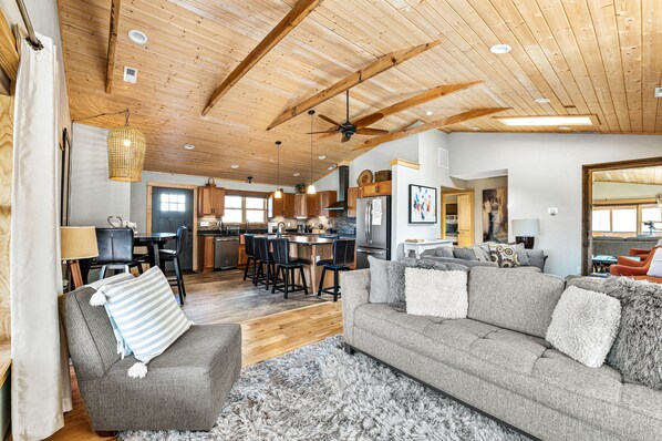 A spacious living area with a sofa, armchair, and a dining area with chairs and a table.