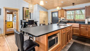 Una cocina moderna con armarios de madera, una isla grande e iluminación colgante.