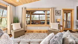 Una sala de estar acogedora con un ventanal grande, techo de madera y vistas al exterior.