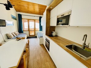 A compact kitchen with a wooden countertop, a built-in oven, and a stainless steel sink.