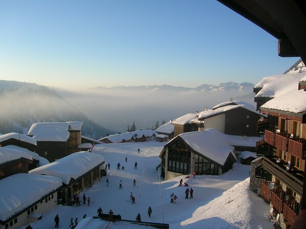 A snow-covered village with traditional wooden buildings and a ski slope.