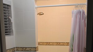 A bathroom with a toilet, a shower with a curtain, and tiled walls. - Cozy Villa 10 minutes walk to riverwalk, Hemispher park and convenstion center. (San Antonio)