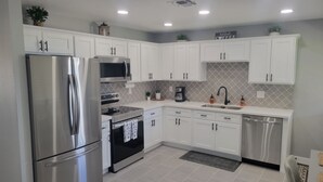A modern kitchen with white cabinets, stainless steel appliances, and a tiled backsplash. - Lodging and entertainment all wrapped into one great place! (Apache Junction)
