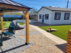 Eine Terrasse mit überdachter Sitzgruppe, einem kleinen Pool und einem Haus im Hintergrund.