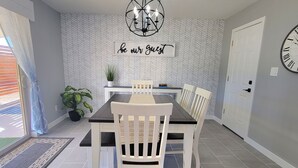 A dining area with a table and chairs, a ceiling fan, a wall-mounted sign, and a door with a clock. - Lodging and entertainment all wrapped into one great place! (Apache Junction)