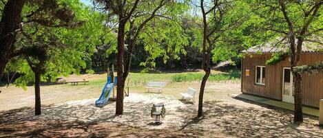 A park with a playground, benches, and a small building.