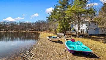 A lakeside property with a dock, boats, and a house.