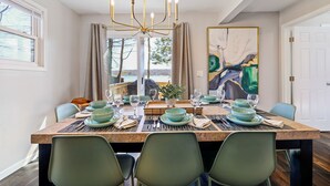 En matplats med ett bord dukat för sex personer, med gröna tallrikar och en kristallkrona.
