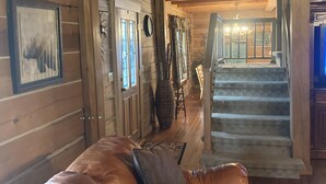 A wooden interior with a leather sofa, a staircase, and a dining area. - log home Only 10 min from Mammoth Cave Nat Park (Park City)