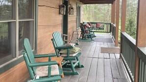 A wooden porch with green rocking chairs and tables, a wooden ceiling, and a view of trees. - log home Only 10 min from Mammoth Cave Nat Park (Park City)