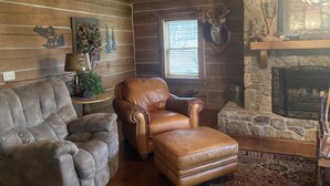A log cabin interior with a stone fireplace, leather armchair, and rustic decor. - log home Only 10 min from Mammoth Cave Nat Park (Park City)